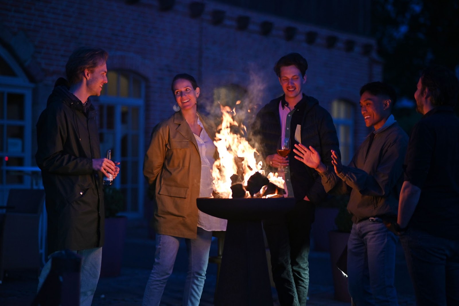 Photo of Leapsome employees standing around a fire pit engaged in conversation