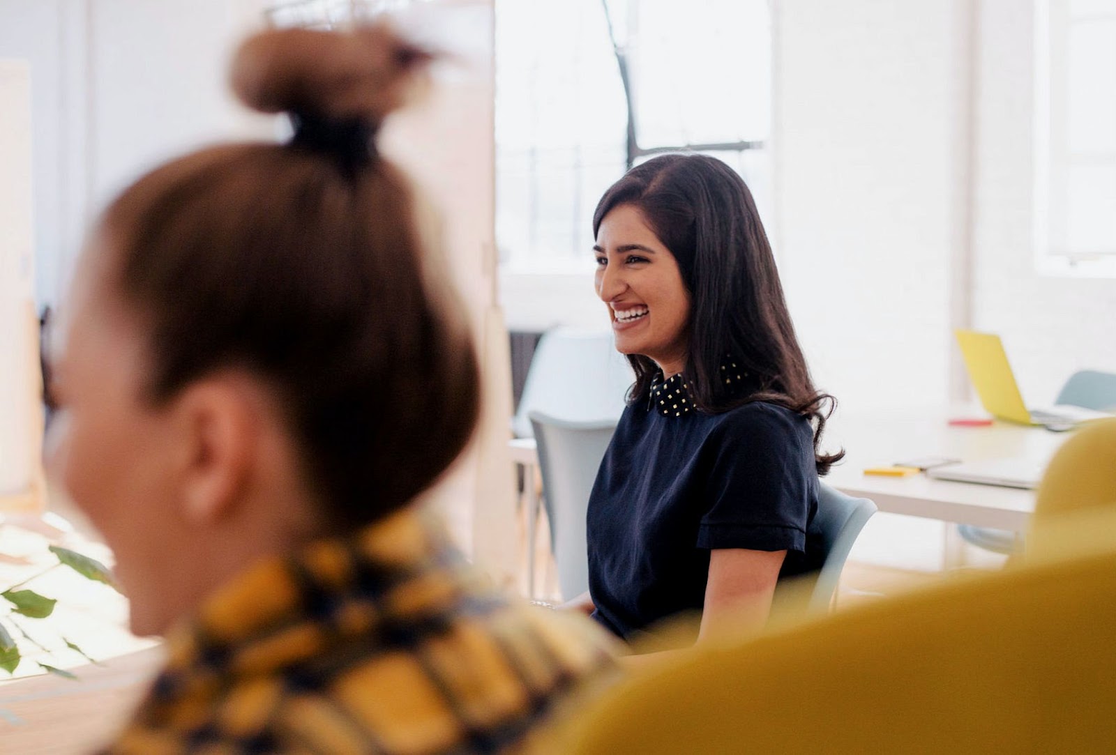 Two professional women are smiling and laughing at work.