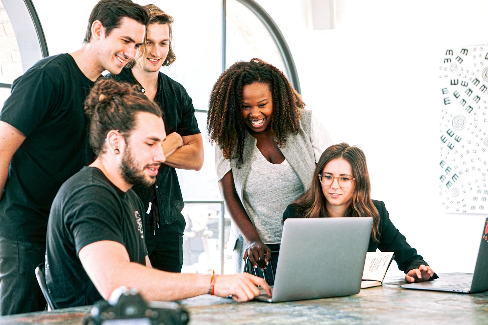 Staff around a laptop looking happy and engaged in the company mission