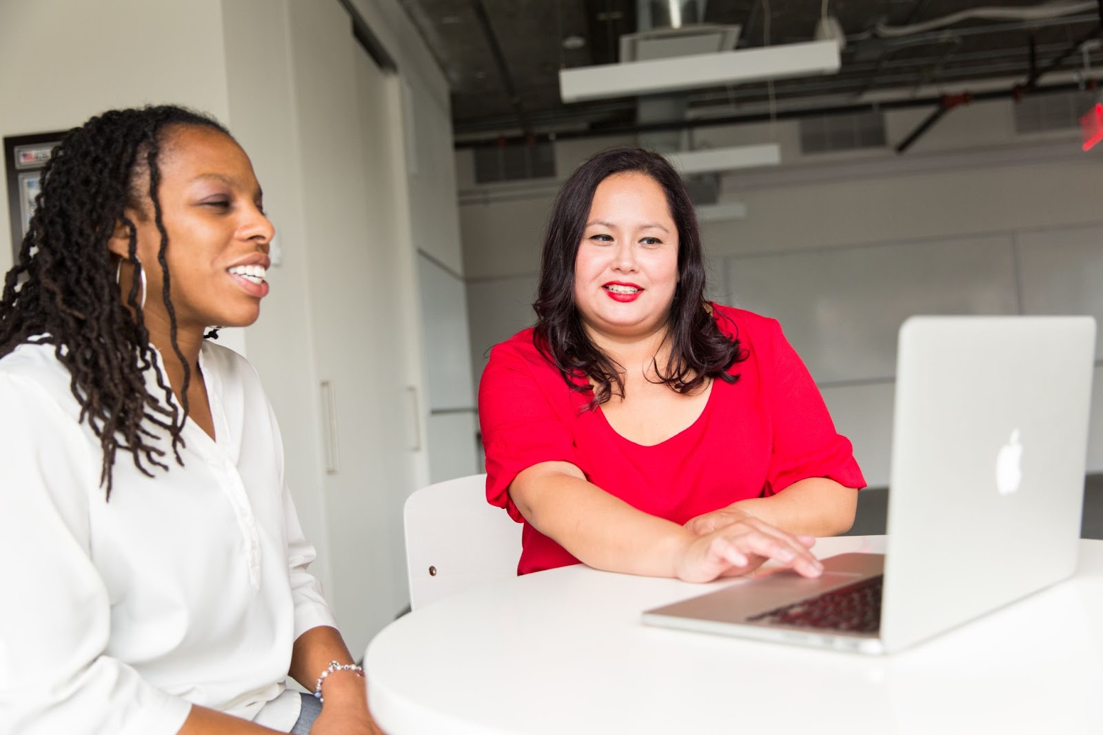 Two women looking at a laptop’s screen in a professional setting