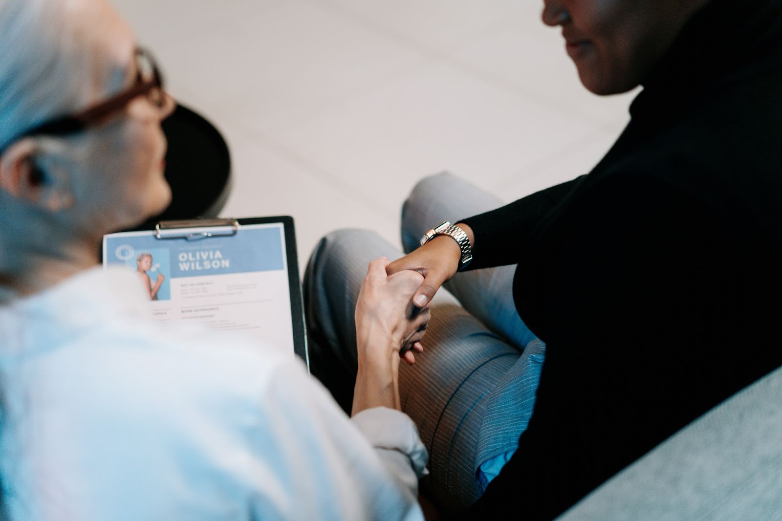 An image of a woman getting a job, and shaking hands with a recruiter.