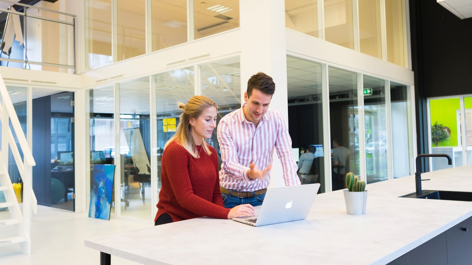 Photo of two professionals looking at a laptop in a modern workspace