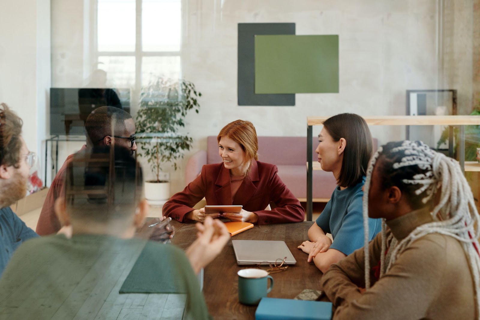 A photo of a team gathered in a meeting around a table.