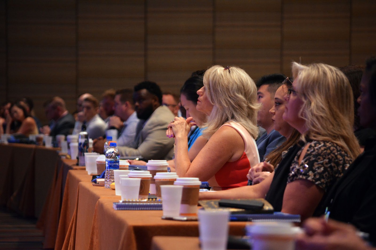 A photo of employees listening to a presentation in a large conference hall.