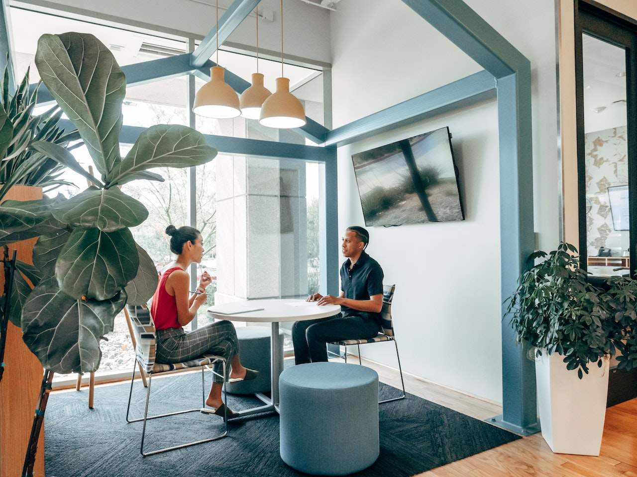 A photo of two professionals sitting together at a table in a casual work environment.