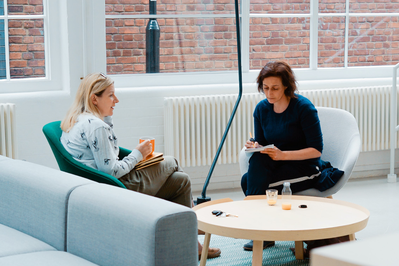 A photograph of two people sitting across from each other, engaged in conversation.