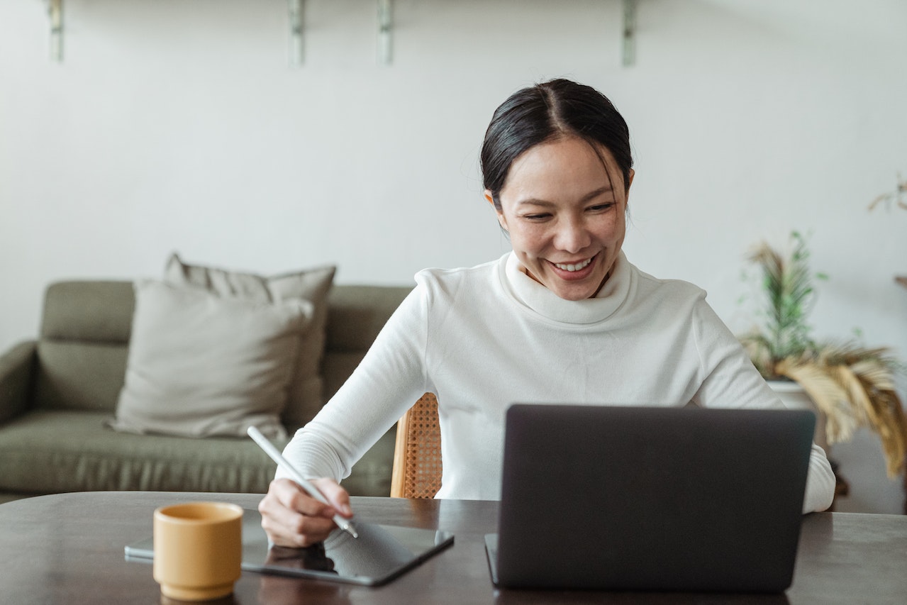 Photo of a smiling professional planning an onboarding process on her laptop.