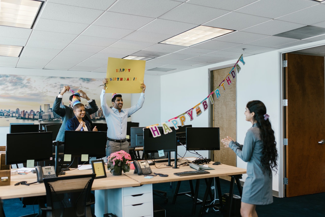 Photo of a group of employees wishing their team member a happy birthday in the office.