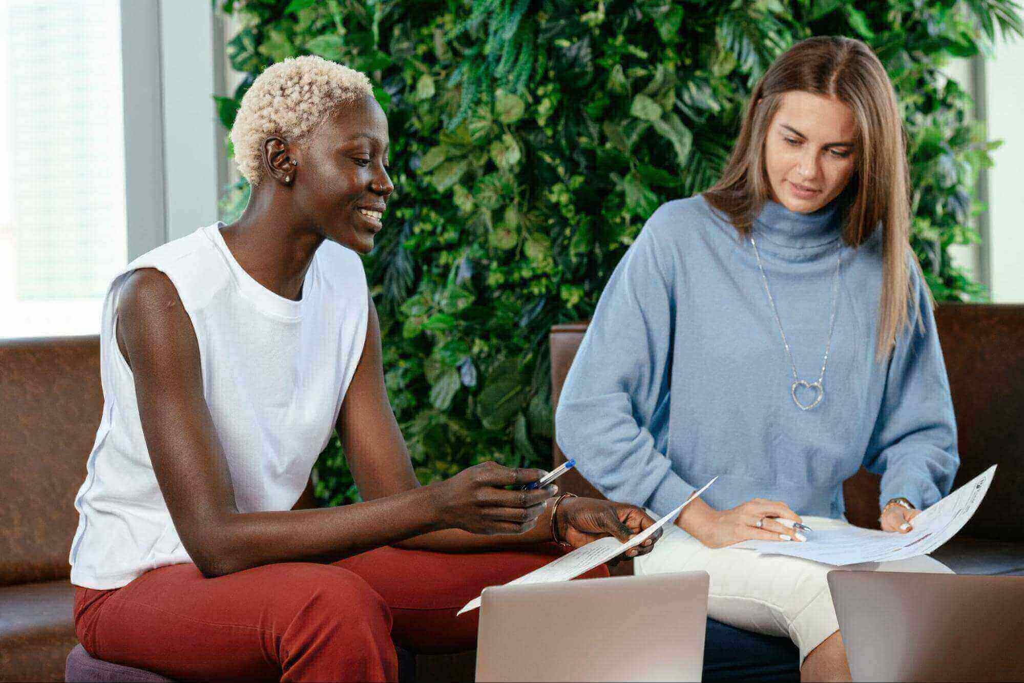 Two professionals having a conversation in a casual work environment.