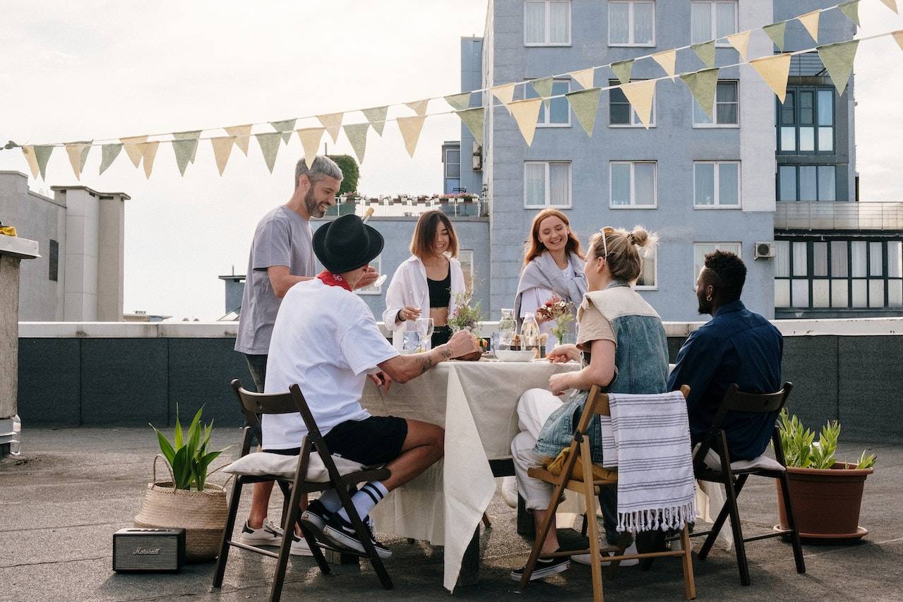 A photo of a group of employees, seated around a dinner table on a roof top.