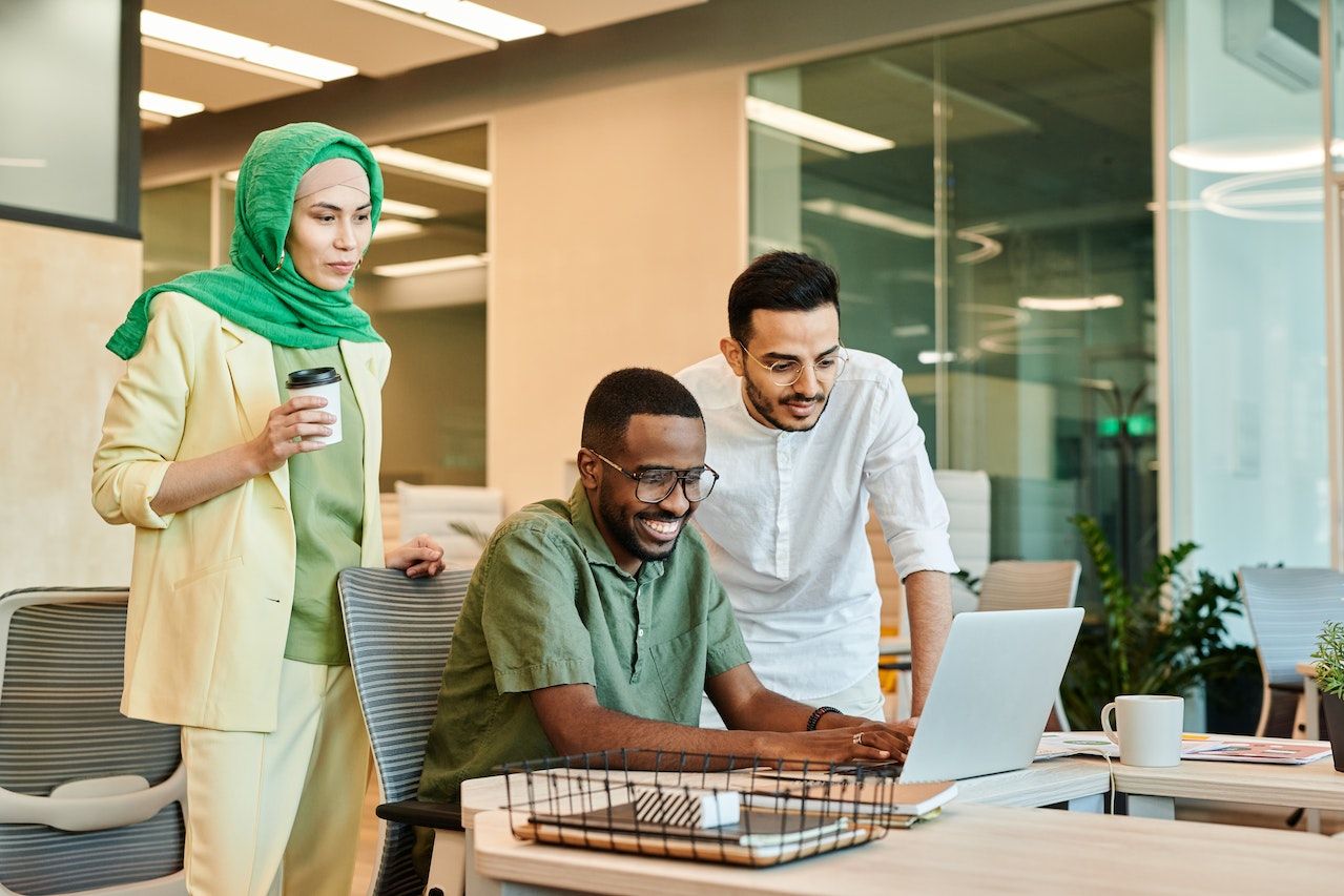 A photo of a group of three professionals looking at a laptop.